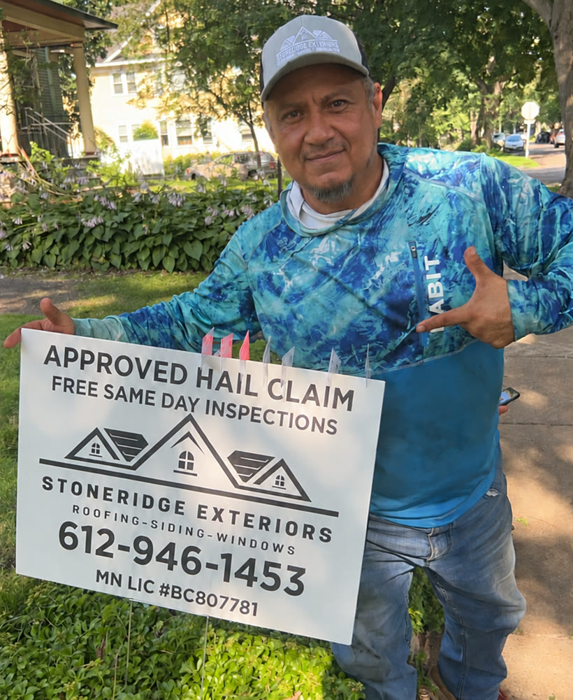 A Stoneridge crew member in a company hat holding a Stoneridge Exteriors yard sign