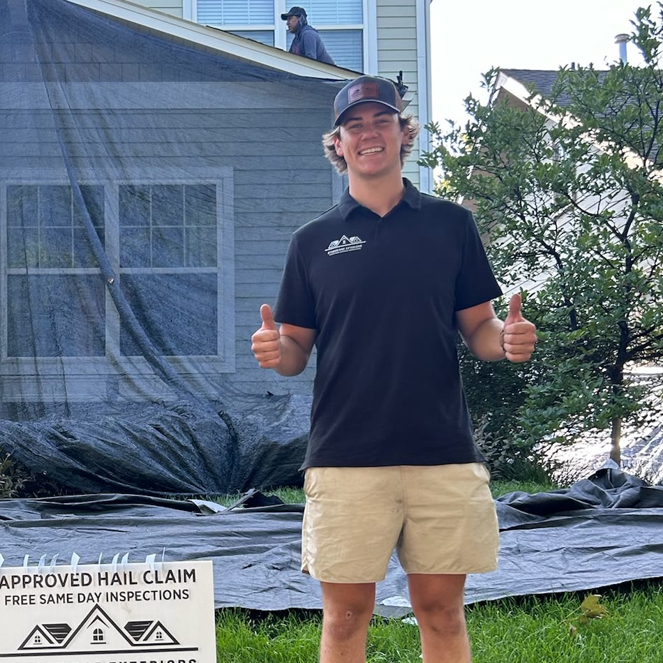 A Stoneridge team member giving two thumbs up in front of a home while the crew works on the roof